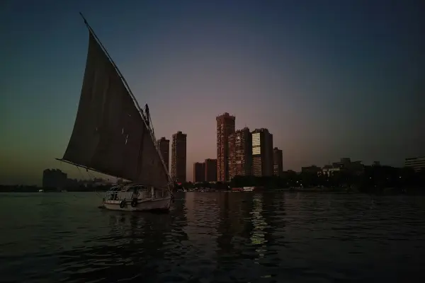 Eine traditionelle Felucca segelt bei Dämmerung auf dem Nil vor der Skyline Kairos