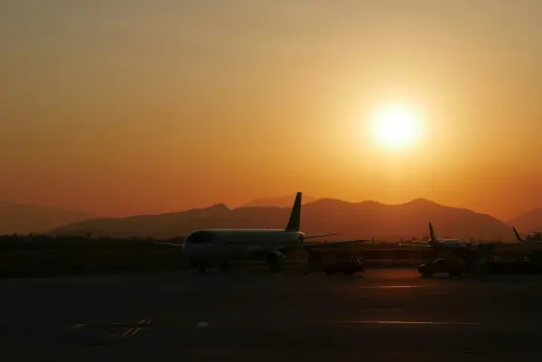Die Silhouette eines Flugzeugs bei Sonnenuntergang auf einem Flughafenvorfeld