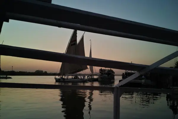 Eine traditionelle Felucca segelt bei Sonnenuntergang auf dem Nil