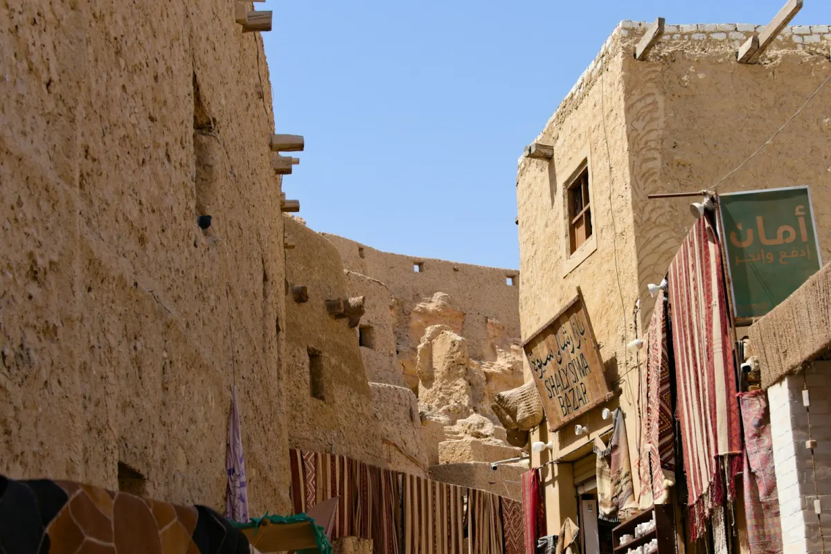 زقاق سوق مشمس فيه منسوجات ومبانٍ من الطوب اللبن في مصر